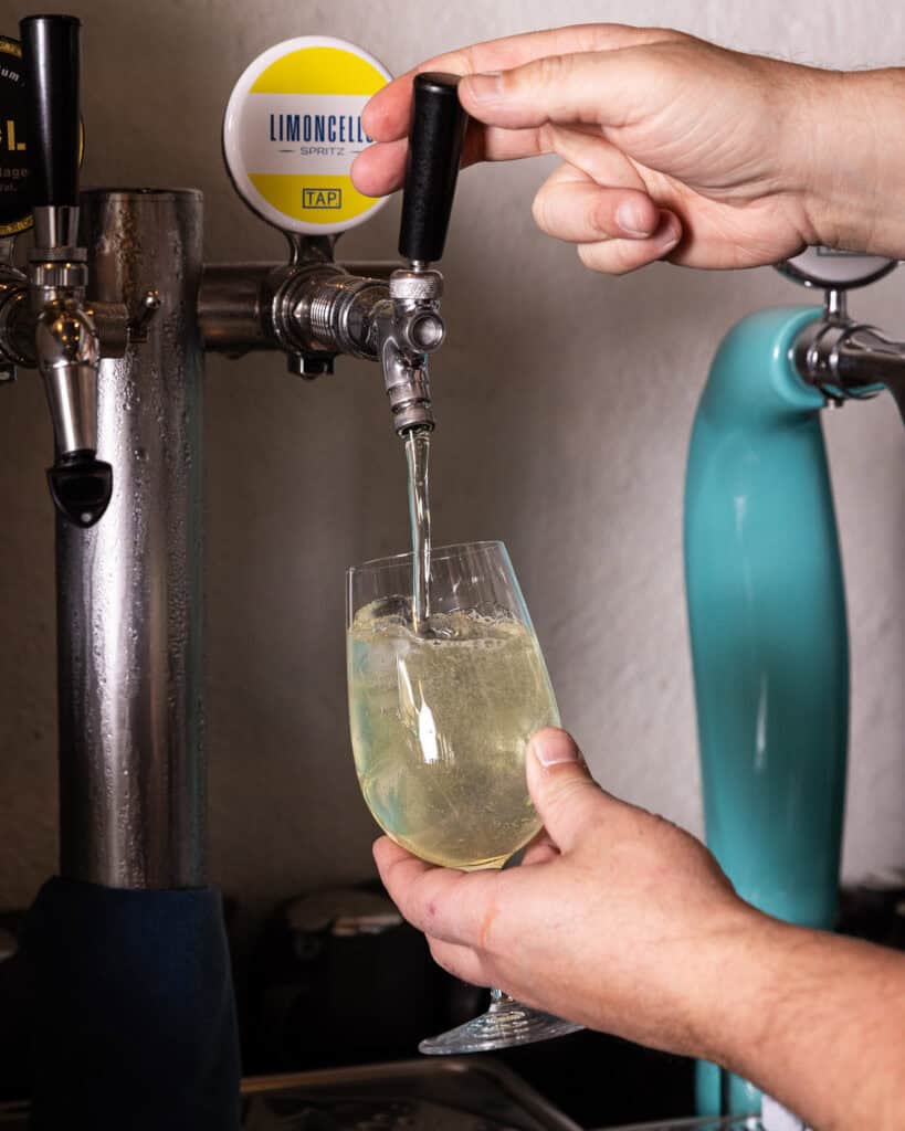 Pouring Limoncello spritz from tap into glass