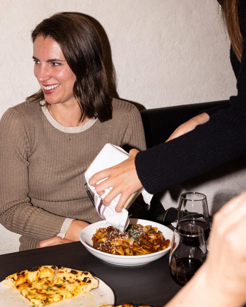 Woman enjoying pasta dish at restaurant.