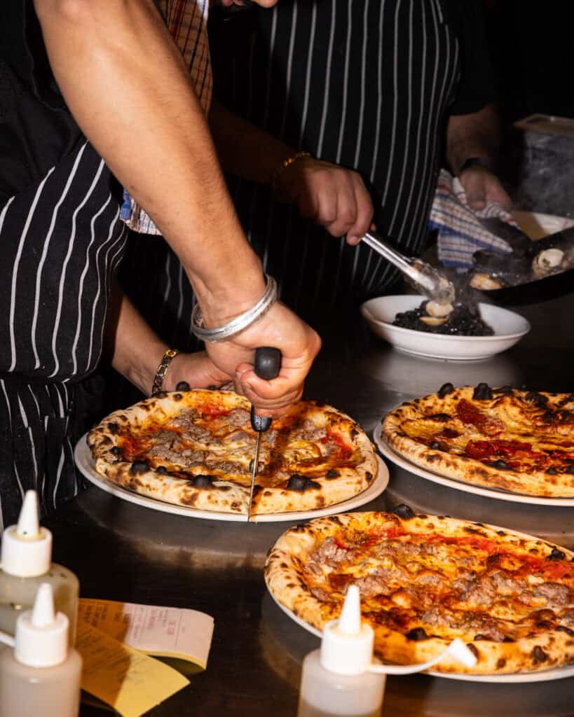 Chef slicing pizza at a restaurant kitchen