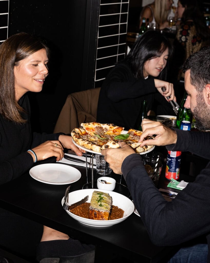 Friends dining with pizza and pasta at restaurant.