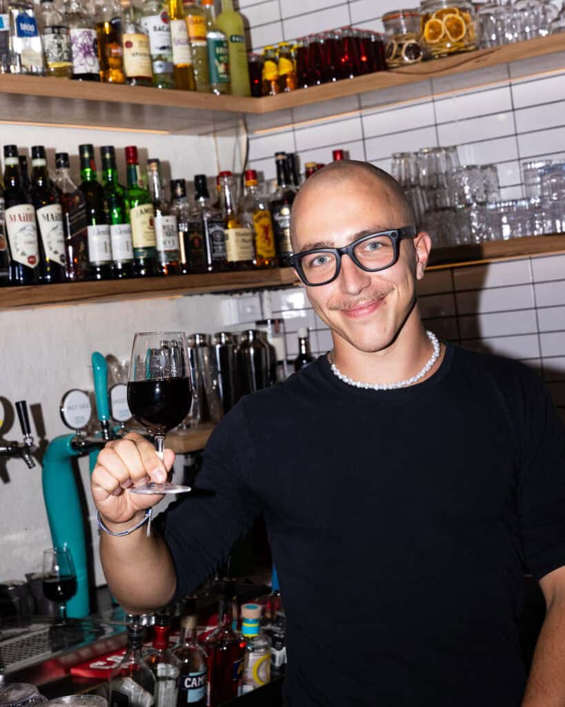 Bartender holding red wine glass in modern bar.