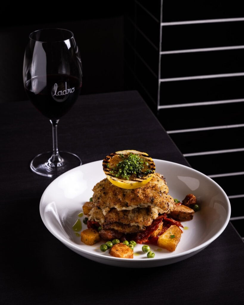 Elegant plated meal with wine glass on dark table.